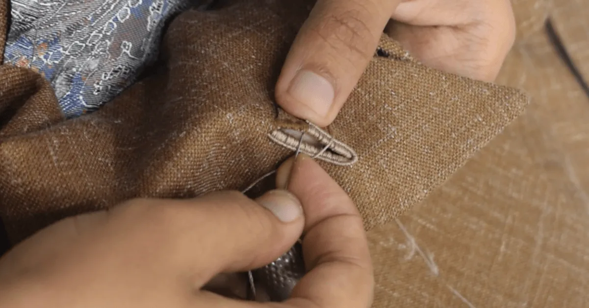 A Laxmi Tailors tailor hand-stitching a suit buttonhole in Jakarta